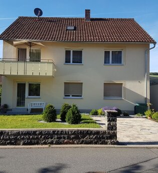 Zweistöckiges gelbes Einfamilienhaus mit Balkon, Garten, gepflasterter Einfahrt und Garage | © Beate Büchold