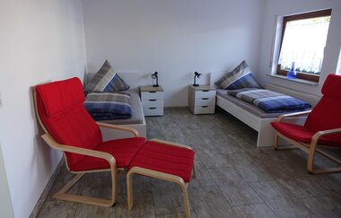 Wohn- und Schlafraum der Ferienwohnung: zwei Einzelbetten und zwei rote Sesselstühle | © Neckar-Zaber-Tourismus e.V.