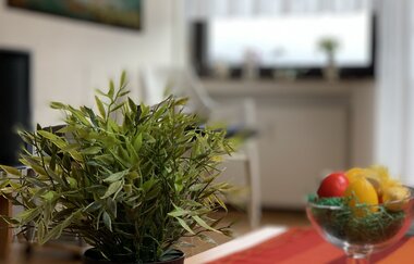 Grüner Topfpflanze auf rot-orange gestreiftem Tischläufer in Wohnzimmer mit unscharfem Hintergrund