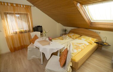 Gelb und Weiß eingerichtetes Doppelzimmer, ein kleiner Tisch mit zwei Stühlen und Kissen. | © Neckar-Zaber-Tourismus e.V.