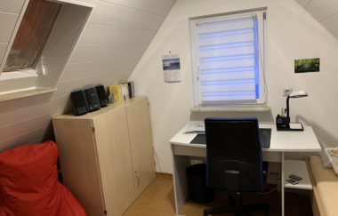 Kleines Zimmer mit weißem Schreibtisch, schwarzem Bürostuhl, Bett mit weißen Bettwäsche und Dachschräge | © Gästehaus Sabine