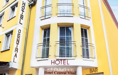 Eingang des gelben Hotel Central Vital mit rotem Teppich, Balkonen und Bar rechts | © Hotel Central