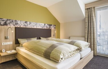 Doppelbett mit Nachttisch, belichtet | © Landpension Kohler