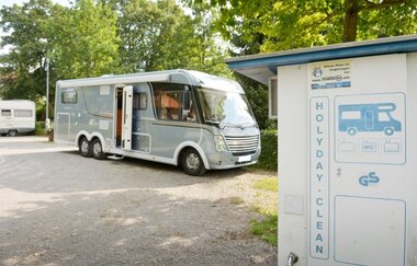 Auf einem Platz steht ein graues Wohnmobil. Dahinter sind Bäume zu sehen. Im Vordergrund stehe eine Clean-Station. Walldürn im Odenwald. | © Stadt Walldürn - Touristinformation