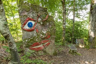 Ein großer Baumstumpf mit einem aufgemalten Gesicht im Wald. Seckach im Odenwald. | © Touristikgemeinschaft Odenwald e.V.