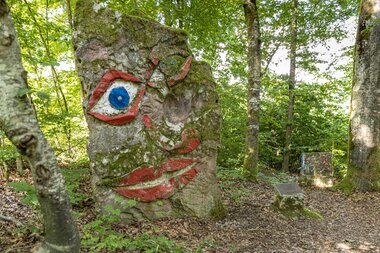 Ein großer Baumstumpf mit einem aufgemalten Gesicht im Wald. Seckach im Odenwald. | © Touristikgemeinschaft Odenwald e.V.