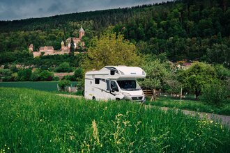 Im Vordergrund ist eine grüne Wiese mit einem Wohnmobil zu sehen. Im Hintergrund ein Schloss. Es handelt sich um das Schloss Zwingenberg am Neckar im Odenwald. | © Touristikgemeinschaft Odenwald