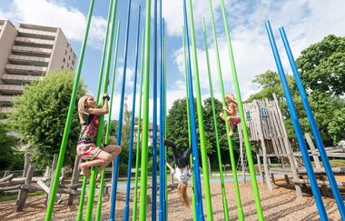 Mehrere Kinder klettern an bunten Stangen hinauf