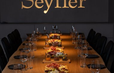 Tagungsraum mit goldenem Schriftzug an Wand "Seyffer", lange Holztafel, eingedeckt mit Essen in der Mitte | © Christian Seyffer