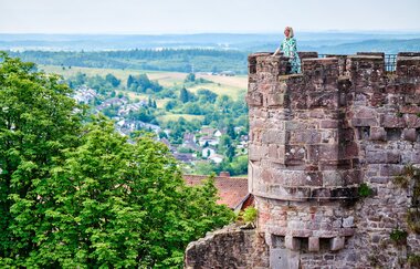 Eine Frau steht auf einem Burgturm und genießt die Aussicht über den Odenwald. | © Landratsamt Rhein-Neckar-Kreis I Florian Trykowski