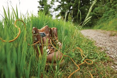 Wanderschuhe stehen in hohem Gras | © TMBW