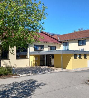 Hellgelbes zweistöckiges Gebäude mit Flachdachvorbau und Metalltreppe ins zweite OG | © Petra Natzkowski