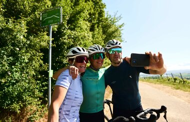 Drei Gravelbiker machen ein Selfie auf einer Tour durch die Weinberge im Land der 1000 Hügel.