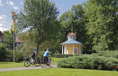 Zwei Radfahrer fahren über den Radweg im Schlosspark.