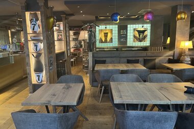 Innenansicht des Restaurants mit Holzboden, farbigen Lampen und Holztischen. | © Walzwerk Schwetzingen