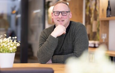 Lucas Schwab sitzt in der Vinothek des Weingutes Heinz J. Schwab | © Touristikgemeinschaft Hohenlohe e. V. | Weingut Heinz J. Schwab