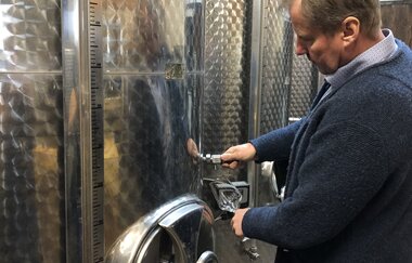 Der Winzer kontrolliert den Wein am Edelstahltank im Weinkeller | © Touristikgemeinschaft Hohenlohe e.V.| Weingut Ungerer