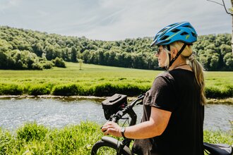 Eine Radfahrerin steht mit ihrem Fahrrad am Jagstufer | © Stadtverwaltung Crailsheim