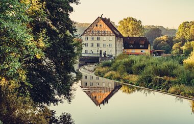 Etappe 4 - Spiegelung in der Jagst am Wehr mit Fachwerkhaus | © Arbeitsgemeinschaft Kocher-Jagst-Radweg