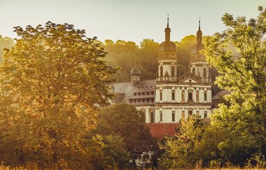 Etappe 4 - Kloster Schöntal aus der Ferne zwischen Bäumen | © Arbeitsgemeinschaft Kocher-Jagst-Radweg