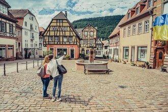 2 Frauen stehen auf dem Marktplatz Neckargemünd, 1 Frau deutet und zeigt der anderen Frau etwas.