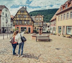 2 Frauen stehen auf dem Marktplatz Neckargemünd, 1 Frau deutet und zeigt der anderen Frau etwas.