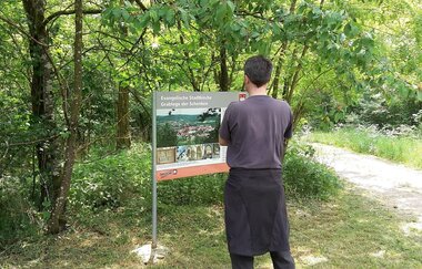 Informationstafel zum Kulturweg am Wegesrand im Wald; Wanderer steht davor und betrachtet die Tafel | © Petra Natzkowski